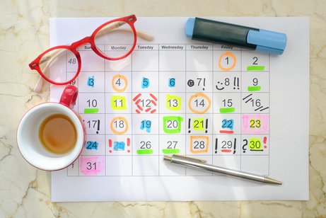 Veranstaltungen VdK Baden-Württemberg Veranstaltungskalender Veranstaltungssuche Monatskalender auf einem Papier, darauf liegen Stifte, daneben steht eine Kaffeetasse und eine Brille. Die Monatstage sind bunt markiert, eingekringelt und hervorgehoben mit verschieden farbigen Stiften.