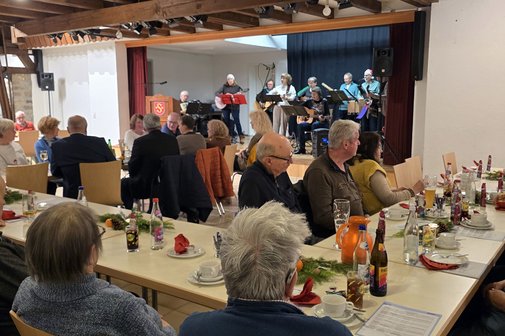 Gäste lauschen der Musik Weihnachtslieder mit der Gitarrengruppe