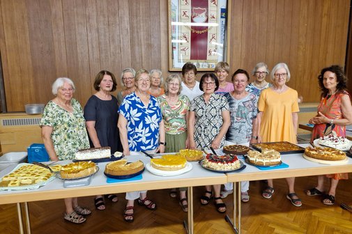 Leckere Kuchen mit Spenderinnen Vordergrund Tische mit 12 verschiedenen selbstgebackenen Kuchen, dahinter die Kuchenspenderinnen